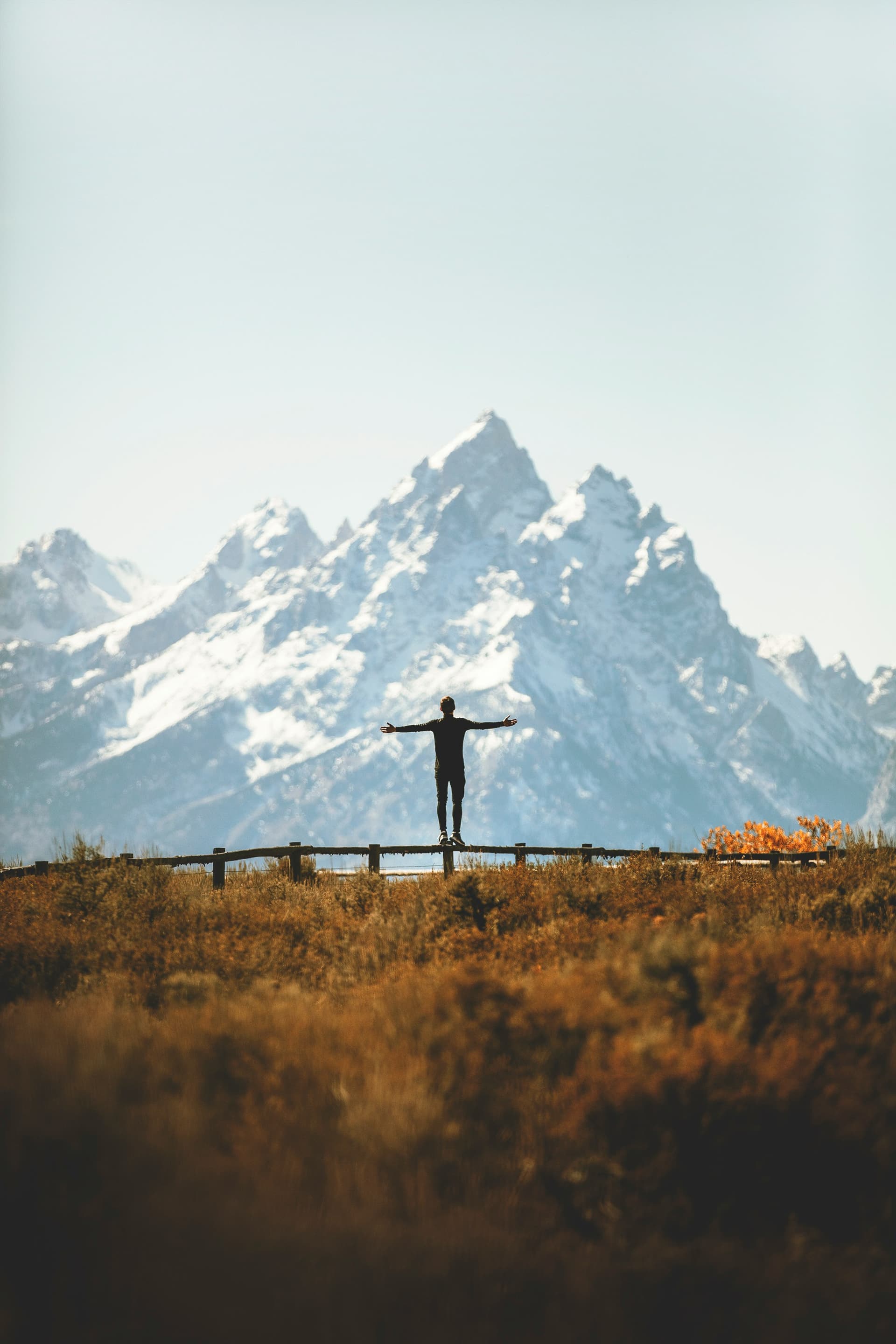 Person standing with open arms in front of mountains